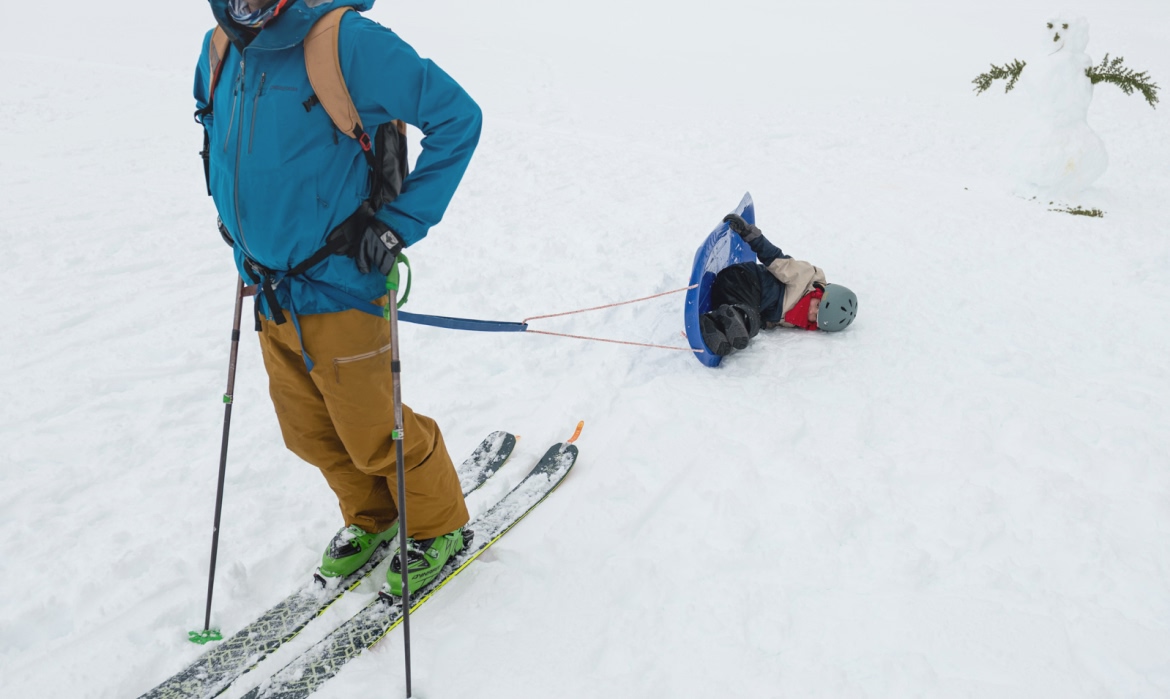 A skier and kid toppled over on a sled