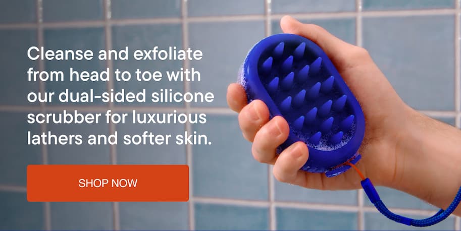 Hand holding Harry's dual-sided silicone scrubber, designed to cleanse and exfoliate scalp and body for fathers and softer skin