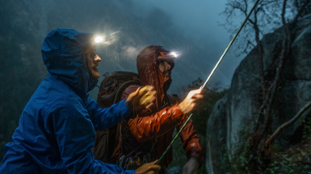 Two climbers rappelling at night in the rain.