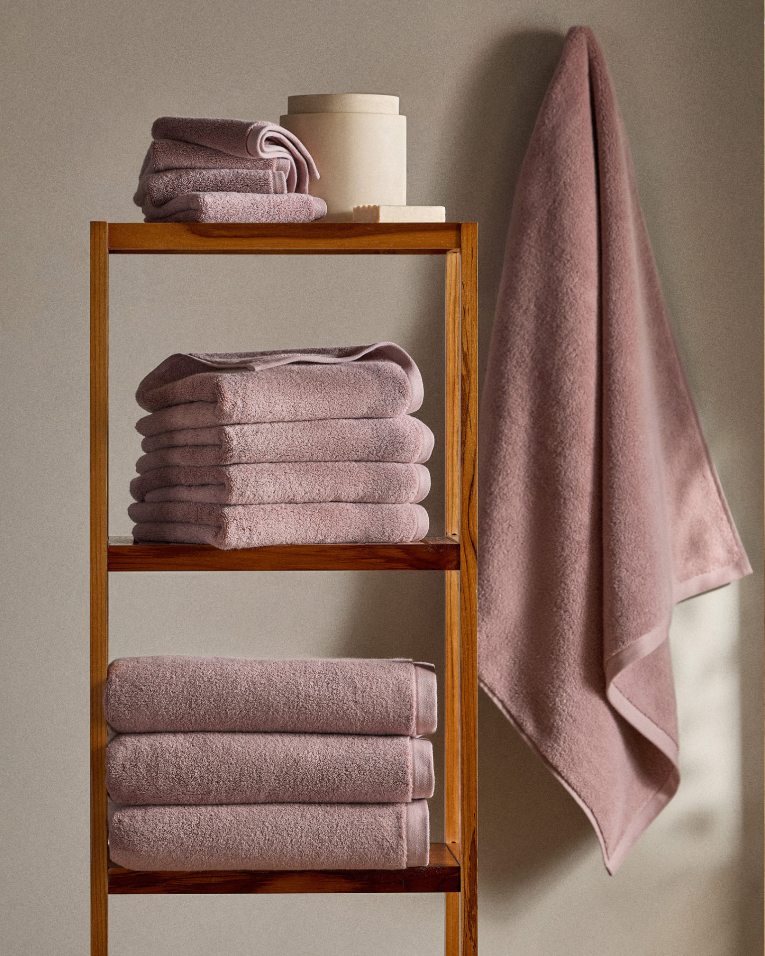 Dusty pink towels stacked on shelf.