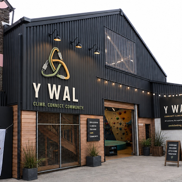 Y Wal climbing centre exterior, with community signage and climbing holds visible through the entrance.