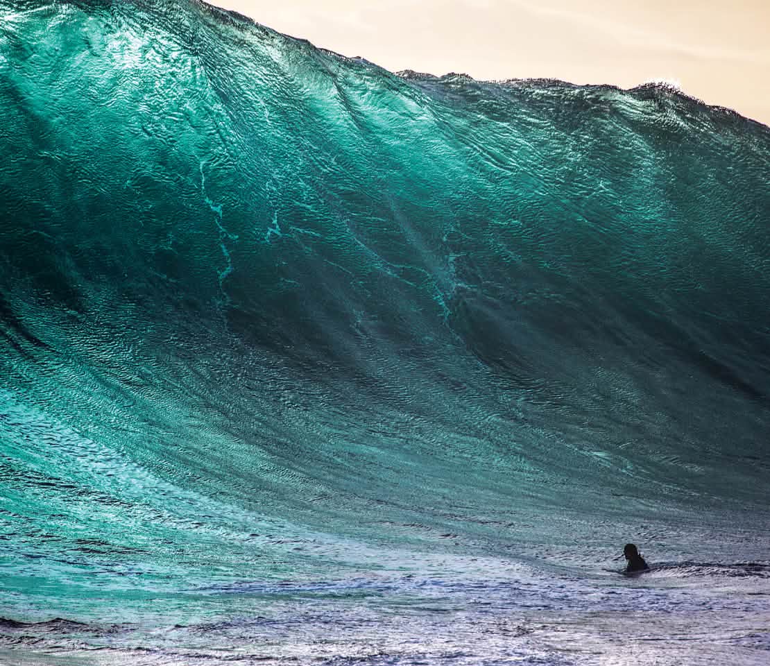 A surfer prepares to duck dive a large wave.