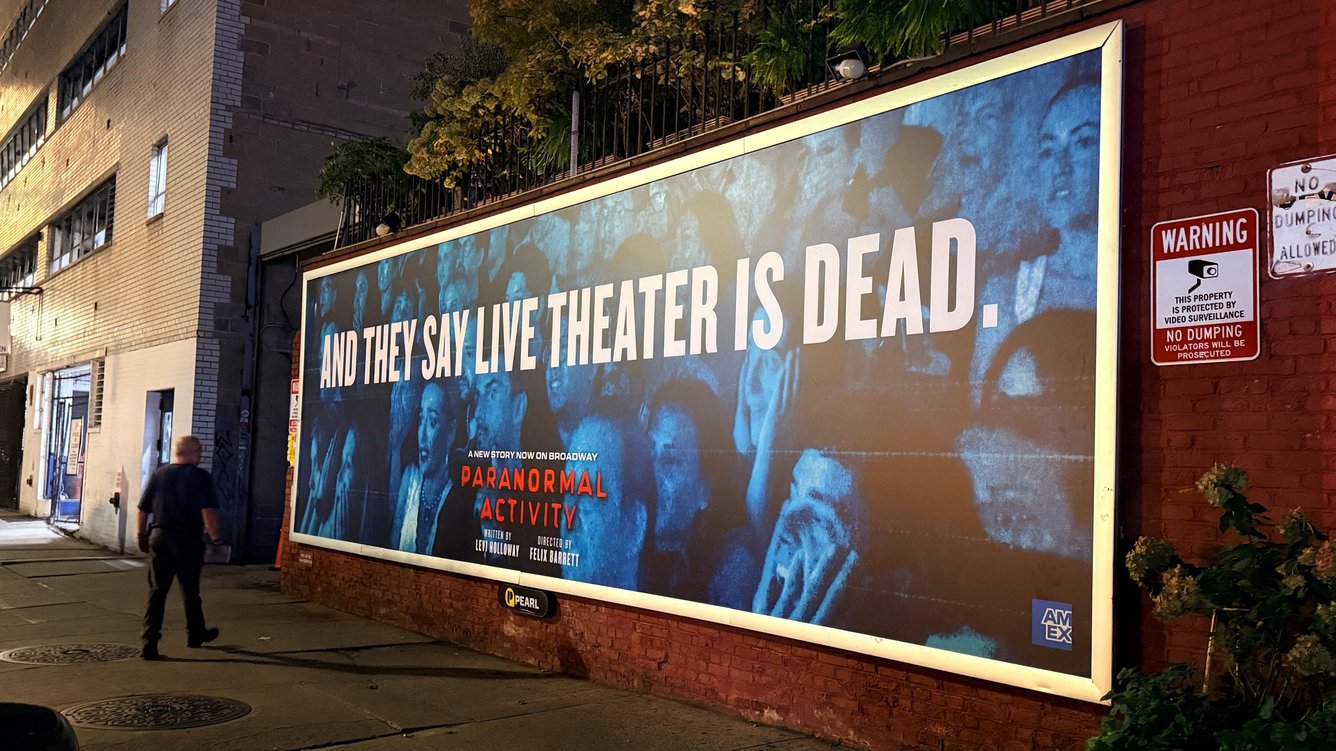 A billboard showing a theater's audiences scared and gasping reactions in blue toned night vision lighting, with the words