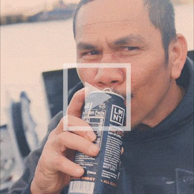 A fisherman drinking a cold LMNT Sparkling to stay hydrated outdoors.