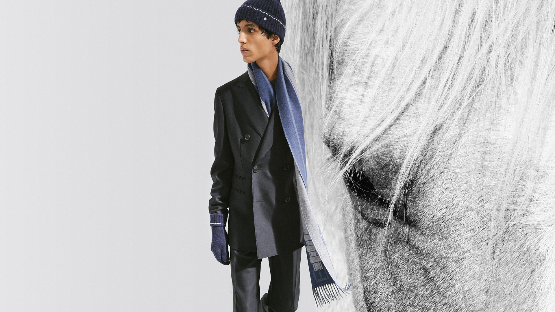 Visual showcasing a man wearing a scarf, hat, and gloves