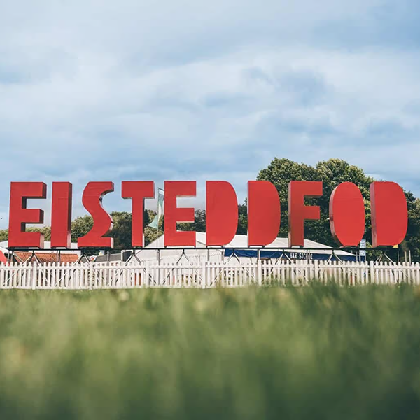 red Eisteddfod sign in field with grass.