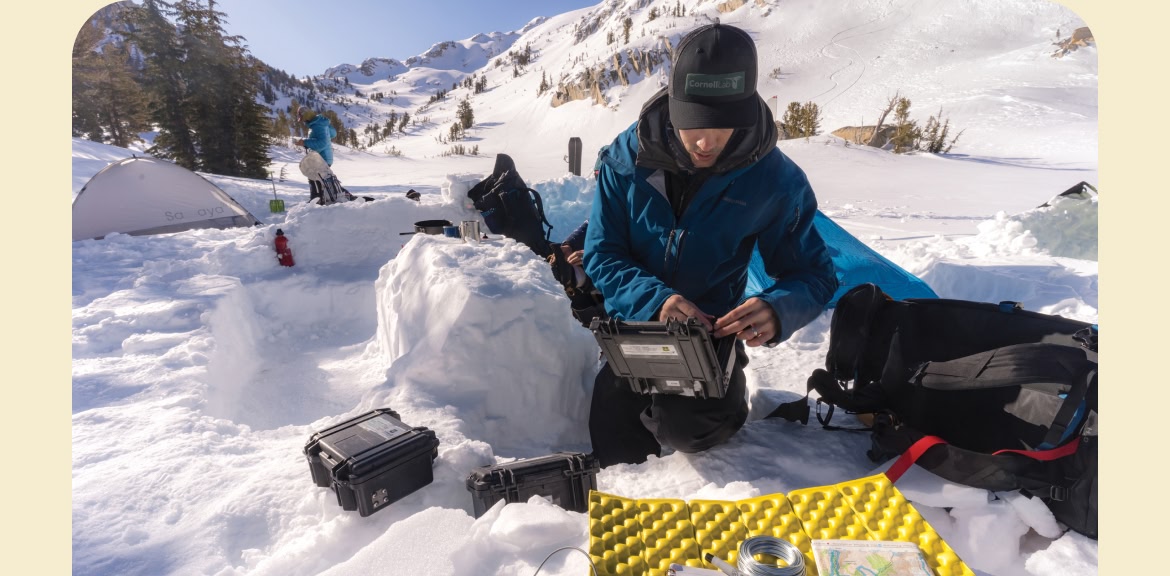  A scientist opens a waterproof case in the snowy backcountry. 