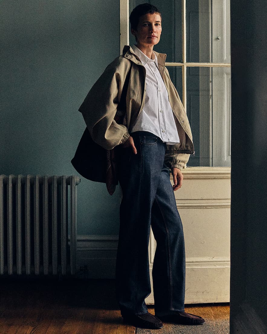 Full body down to knees image of man looking to the left of the image. He wears Super Zero&reg; Hiut jeans, light brown jackets, navy wool jumper over white shirt. 
