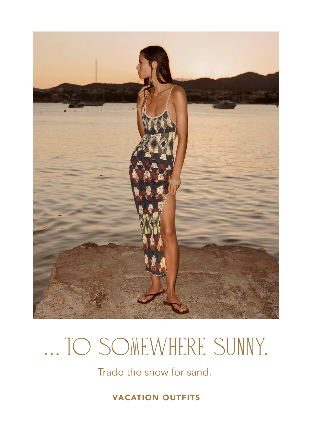 Model standing on a stone pier by the water at sunset wearing a patterned sleeveless midi dress with a high side slit paired with flip-flops, above text reading "... TO SOMEWHERE SUNNY. Trade the snow for sand. VACATION OUTFITS".