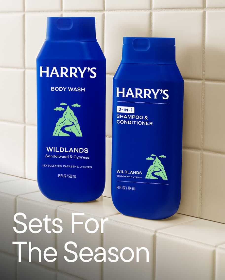 Two Harry's body wash bottles. Mid-Glades scent and a blue variant &mdash; surrounded by foliage, with the headline: Sets For The Season