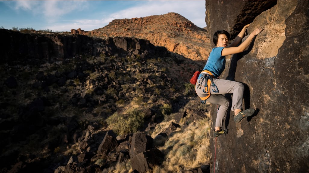  A person climbs a rock in a desert landscape.