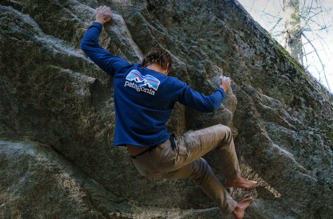  A person climbing a boulder barefoot.