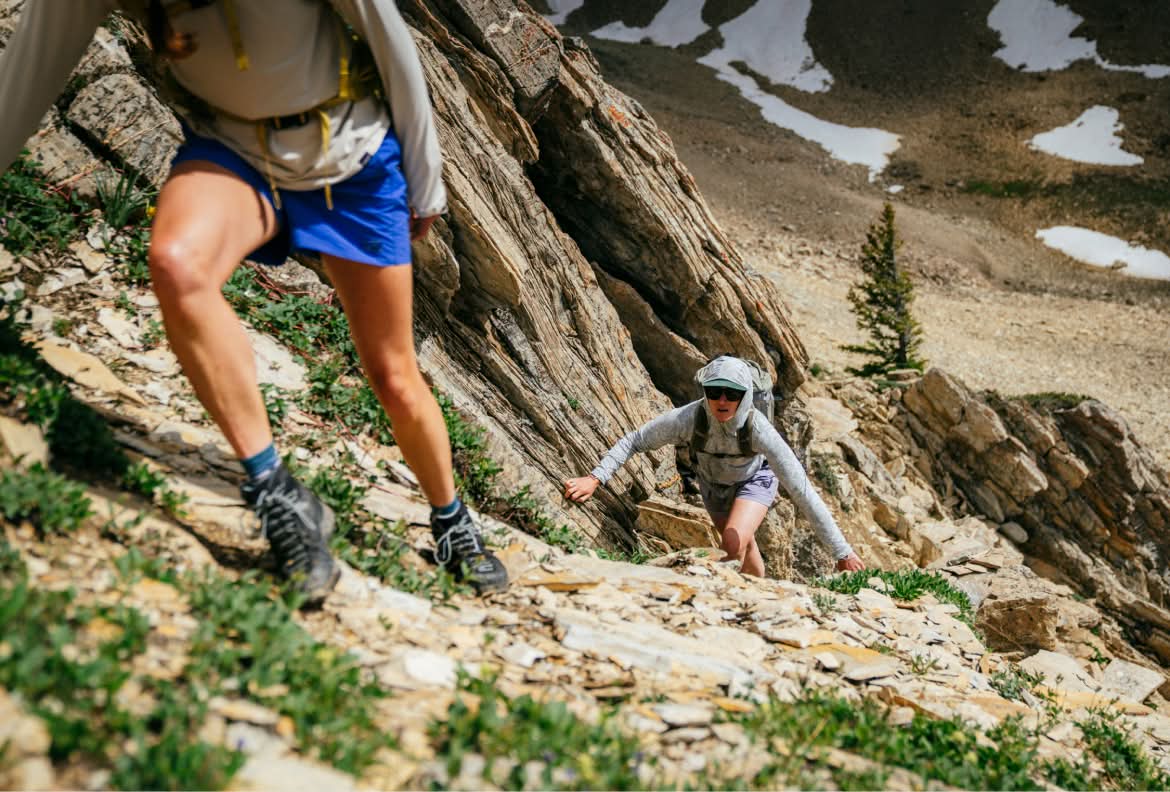 Two people scrambling up a rocky mountainside.