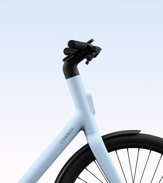 A front-facing view of the Cowboy bike in the Breeze colorway, highlighting the sleek handlebar design, integrated front light, and smart display.