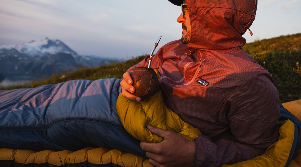 A person sipping from a mate gourd in their sleeping bag.