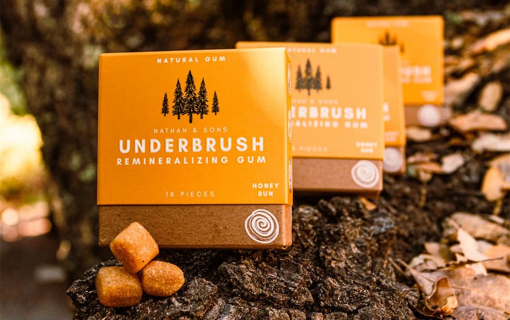 Honey Bun gum boxes lined up on tree bark next to honey chews