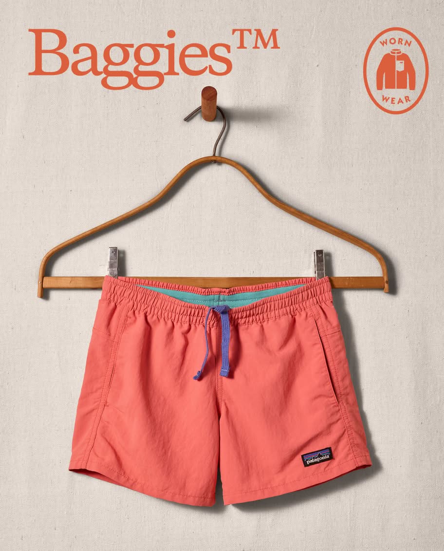 A pair of coral Baggies&trade; Shorts hangs on a clothes hanger.