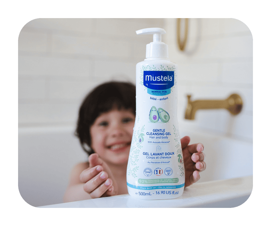 A brother and sister blowing bubbles with a Mustela product in the background