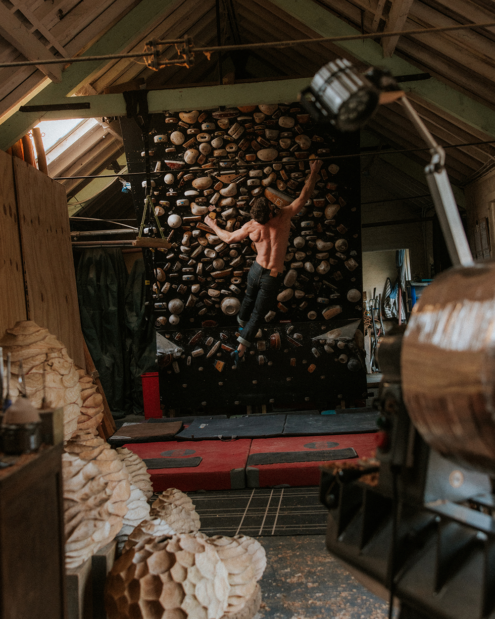 Oliver climbs bouldering wall inside of his studio, surrounded by his artwork.